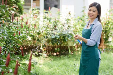 Onun bitkiler hakkında o bahçede açık havada hosepipe ile sulama dikkat çekici genç kadın