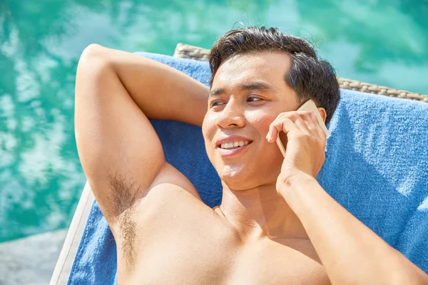 Lächelnder Schöner Junger Mann Liegt Auf Chaiselongue Und Telefoniert — Stockfoto