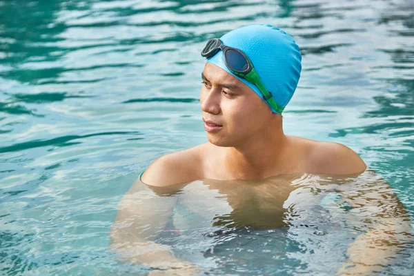 英俊的年轻游泳者在水中休息的橡胶帽子 — 图库照片