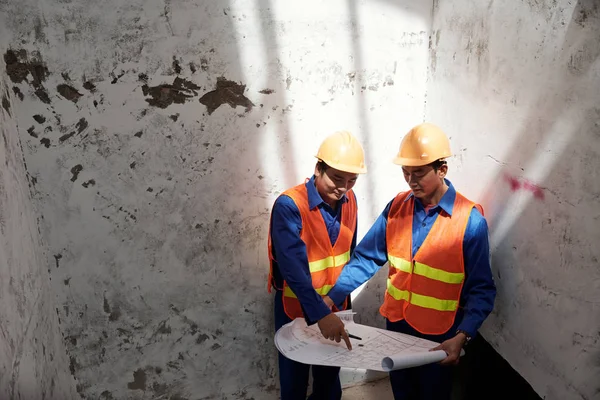 Mimar ve pejmürde duvarlar arasında duran ve planı tartışmaya yüklenici