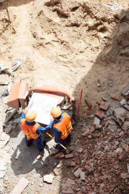 Blueprint inşaat sahasında bakarak inşaatçılar görüntülemek yukarıdan