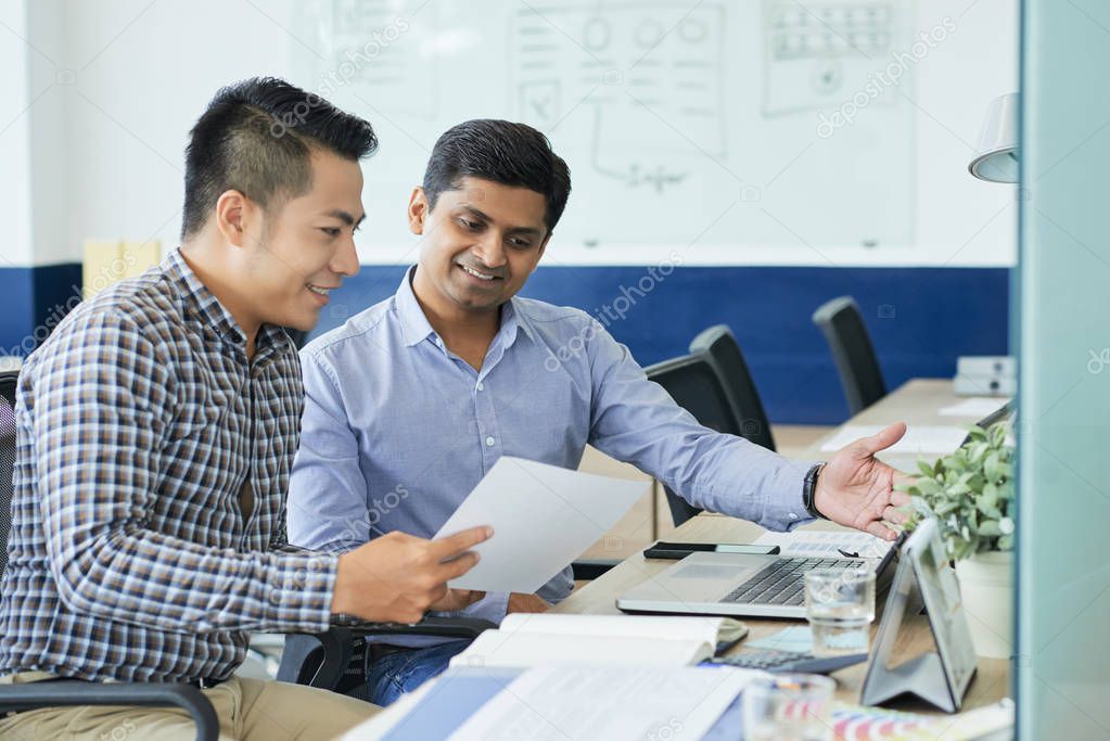 Vietnamese UX designer showing his ideas to Indian coworker