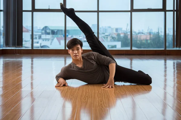 Азиатский Мужчина Поднимает Ногу Смотрит Камеру Танцуя Полу Современной Студии — стоковое фото