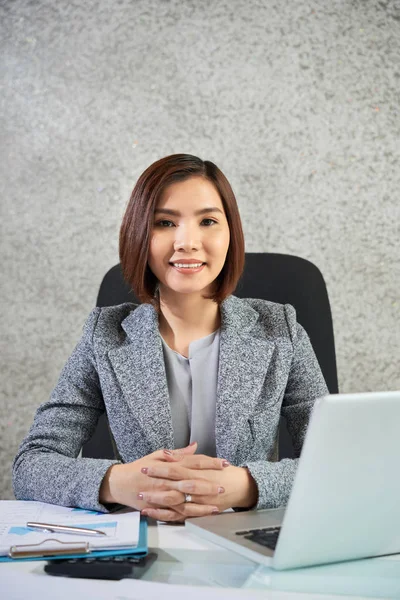 微笑的年轻亚洲女商人的肖像坐在她的工作场所 并与笔记本电脑和金融图表的工作 — 图库照片