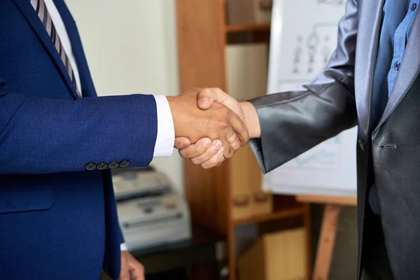 Close-up of two men in suits greeting to each other at business meeting