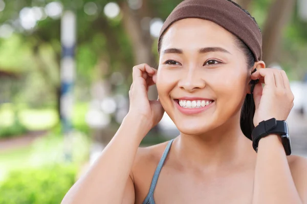 Young Happy Asian Woman Wearing Headband Putting Headphones While Working — Stock Photo, Image