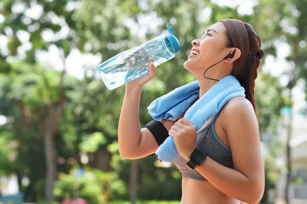 Zijaanzicht Van Lachende Aziatische Sportvrouw Met Handdoek Drinkwater Uit Fles — Stockfoto