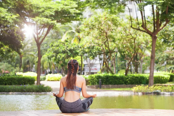 日光の公園池のテラスに座って 瞑想はスポーツ ウエアで匿名のブルネットの背面図 — ストック写真