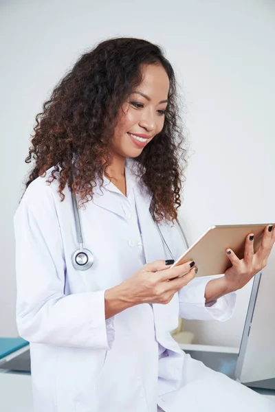 Médica Feminina Uniforme Sentada Escritório Olhando Algo Tablet Digital Sorrindo — Fotografia de Stock
