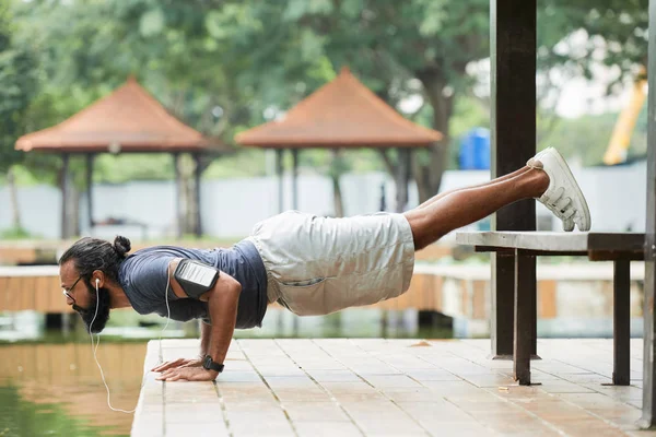 胡子印度运动员与智能手机在他的肩膀做俯卧撑户外和听音乐与耳机 — 图库照片