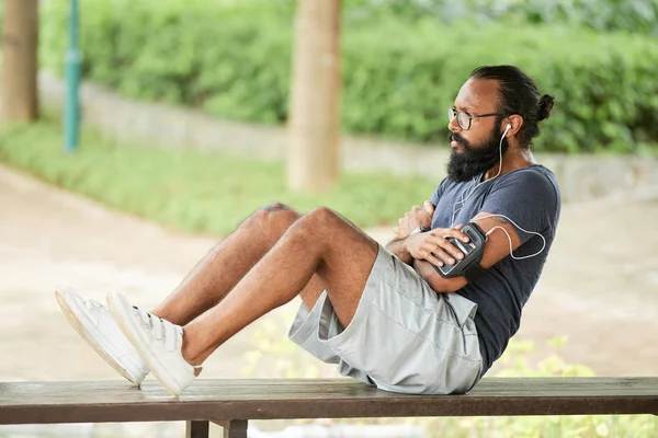 Handsome Man Beard Listening Music Earphones While Doing Abdominal Crunches — Stock Photo, Image