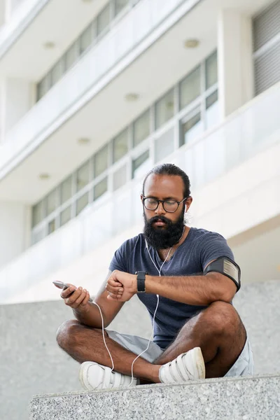 Muscular Bearded Indian Man Glasses Listening Music Earbuds Checking Time — Φωτογραφία Αρχείου