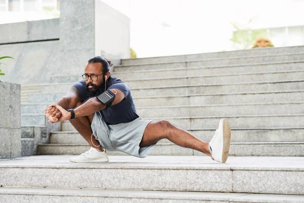 メガネ具体的な屋外のストレッチ体操を行うと 実行する前に音楽を聴くことで運動のひげを生やしたインド人 — ストック写真