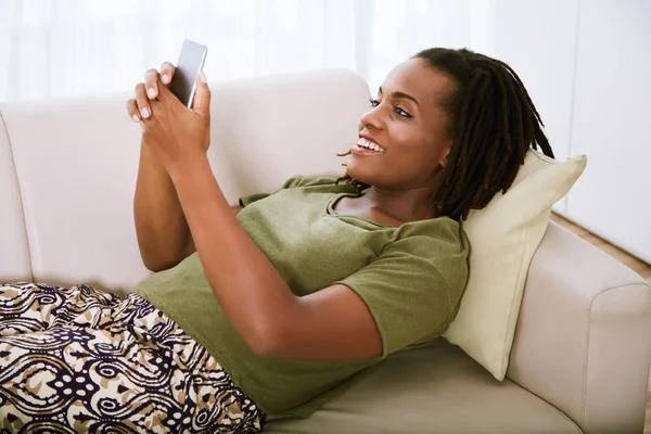 Cheerful Young African American Woman Lying Sofa Texting Friends — Stock Photo, Image