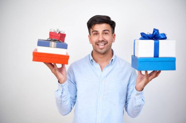 Delikanlı tatil ayakta beyaz arka plan için çeşitli hediye kutuları tutarak gömlek gülümseyen portresi