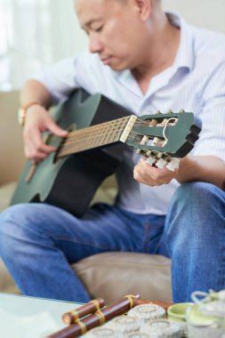 Olgun Asyalı adam gitar, seçici odak ayarlama