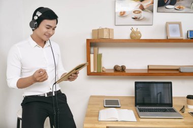 Kulaklık genç iş adamı ve onun işyerinde ofiste otururken dijital tablet üzerinde online görüşme vardır