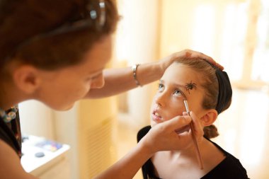 Genç kadının yüz oturma ve sabırla bekleyen küçük kızının iyi Cadılar Bayramı makyaj yapması