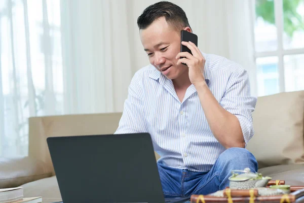 Knappe Positieve Volwassen Man Praten Telefoon Werken Laptop Thuis — Stockfoto