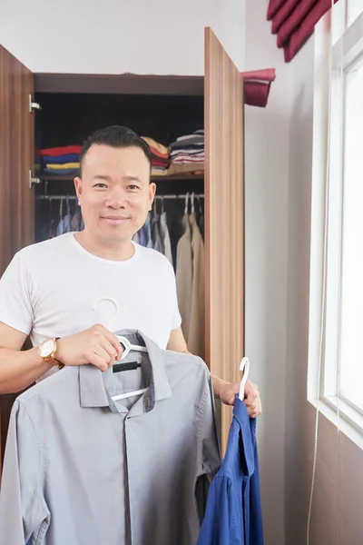 Улыбающийся Взрослый Азиат Выбирает Рубашки — стоковое фото