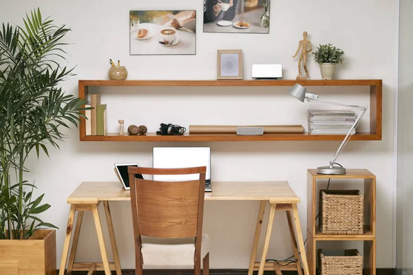 ノート パソコンとデジタル タブレットの快適な椅子とその上 壁に設計された棚の空木製オフィス デスク — ストック写真