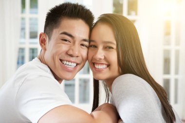 Güzel genç karma yarış çift kanepe yüz yüze ve kamera gülümseyerek oturan