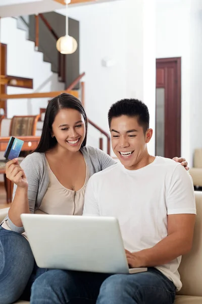 Excited young couple with credit card making orders online