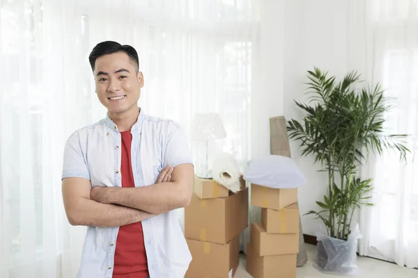 手を渡り 新しい家の明るい部屋でカメラに笑顔で立っている陽気なアジア男 — ストック写真