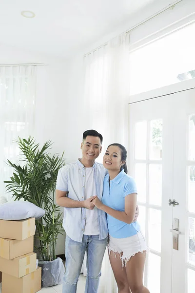 愉快的亚洲女人和男人拥抱和看着相机在新公寓的光室 — 图库照片