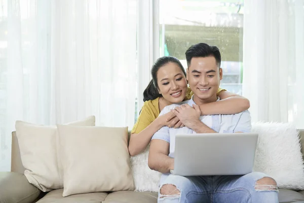 Mujer Abrazando Hombre Feliz Espalda Sentado Sofá Viendo Ordenador Portátil — Foto de Stock