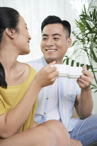 Ontspannende Aziatische Paar Rammelende Met Koffie Kopjes Zittend Bank Kijken — Stockfoto