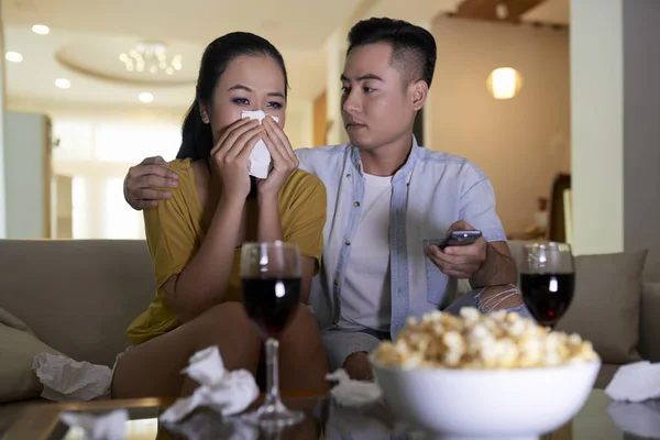 年轻的一对亚洲夫妇看悲伤的电影和男人安慰哭泣的女人 而坐在沙发上 — 图库照片