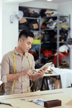 Asya genç erkek stilist ayakta ve önce dijital tablet bakarak başlamak çalışmak