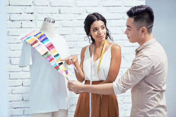 年轻的女设计师建议选择一种颜色的衬衫给她的客户在工作室 — 图库照片