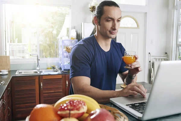 Frowning Man Drinking Glass Juice Working Laptop Kitchen — Stock Fotó