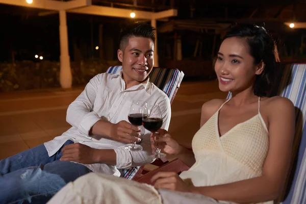 愉快的年轻亚洲夫妇坐在躺椅上 喝着红酒敬酒 在户外庆祝 — 图库照片
