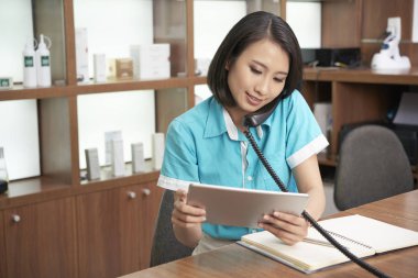 Spa salonda çalışma ve tablet izlerken telefon sahip güzel Asyalı kadın