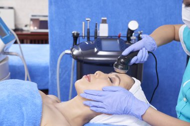 Masanın üzerinde yatan ve rahatlatıcı yüz prosedür profesyonel ekipman ile zevk rahatlatıcı Asyalı kadın yan görünüm