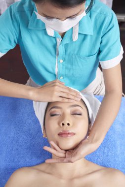 Asyalı kadın havlu ihale yüz Masaj sahip spa salonda yatan görüntüsünü yukarıda