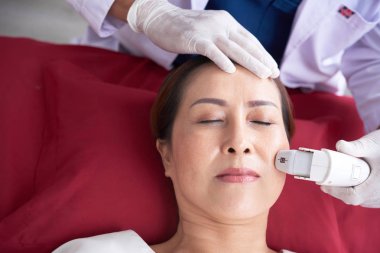 Bazı gençleştirme prosedür yapma güzellik uzmanı kapalı gözlerle yalan kadın yüz Close-up