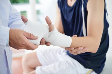 El ve bilek anonim adamın el sarmak için aseptik bandaj kullanarak kırpma pratisyen yaralı