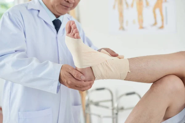 Unerkennbarer Erwachsener Arzt Wickelt Saubere Binde Sorgfältig Fuß Und Knöchel — Stockfoto