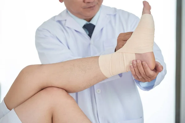 Unrecognizable Medical Practitioner Fastening Bandage Injured Leg Crop Man While — Stock Photo, Image