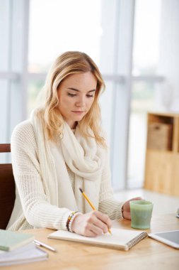 Genç ve güzel kız öğrenci ders kitabı masada evde kahve reklam alarak notları içme