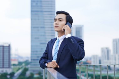 Telefonla arama ve büyük şehir çatıda seyir yakışıklı genç Vietnamlı işadamı