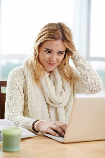 混乱の若い女性が彼女のラップトップ上のタスクで電子メールを読むときに頭をスクラッチ — ストック写真