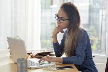 Dalgın oldukça Vietnam kadın gözlük dizüstü bilgisayar ekranındaki bilgileri okuma