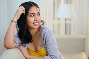 Genç ve güzel Filipino kadın evde koltukta dinleniyor