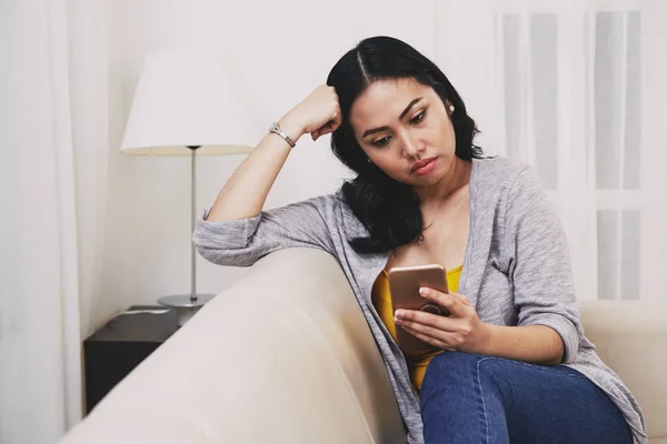 悲伤的沉思的年轻菲律宾妇女阅读短信或新闻在智能手机上 — 图库照片