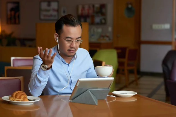 Vietnamese entrepreneur drinking coffee and video calling his business partner